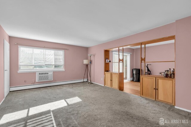 unfurnished room featuring light colored carpet, plenty of natural light, baseboard heating, and a wall unit AC