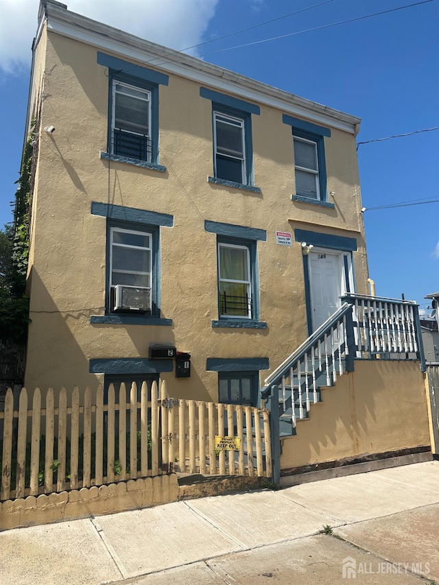 146 Seaman St, New Brunswick, NJ 08901 - view of front of home with stucco siding, a fenced front yard, and cooling unit