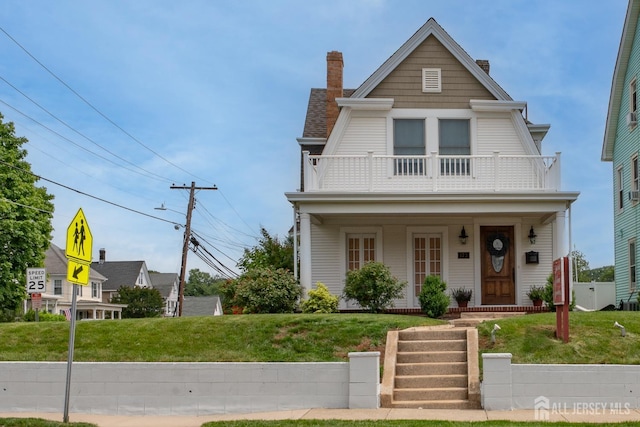 173 N Main St, Milltown, NJ 08850 - view of front of home with a balcony, a chimney, covered porch, and a front yard