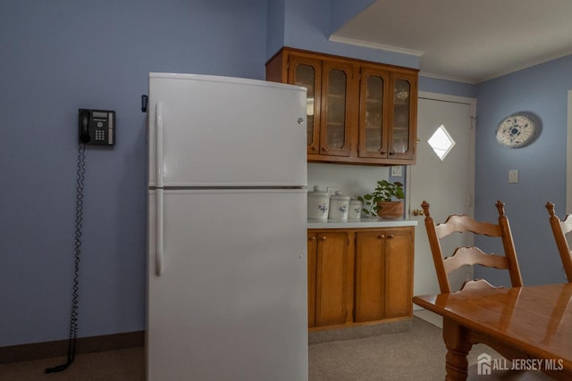 173 N Main St, Milltown, NJ 08850 - kitchen with freestanding refrigerator, brown cabinets, carpet flooring, glass insert cabinets, and light countertops