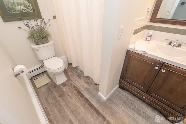 173 N Main St, Milltown, NJ 08850 - bathroom featuring wood finished floors, vanity, a baseboard heating unit, tasteful backsplash, and curtained shower