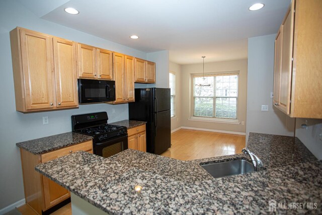 kitchen with black appliances, a sink, light wood-style floors, baseboards, and recessed lighting