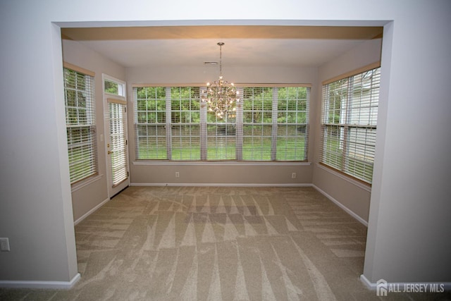 unfurnished dining area featuring baseboards, carpet floors, and a chandelier