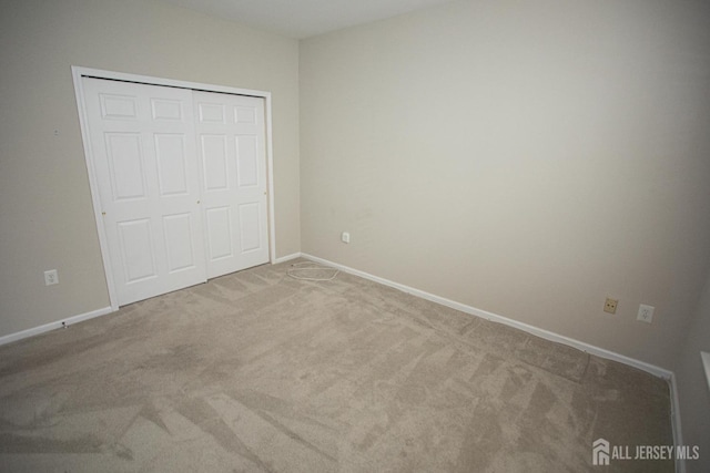 unfurnished bedroom featuring carpet flooring, baseboards, and a closet