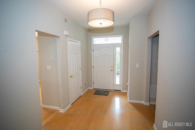foyer entrance with light wood-style flooring and baseboards