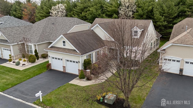 view of front of home featuring asphalt driveway, a front yard, a garage, a shingled roof, and stone siding