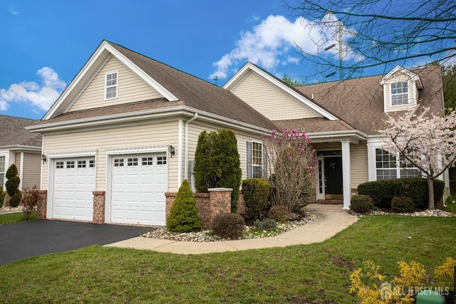 view of front facade featuring asphalt driveway, a front yard, a shingled roof, and a garage