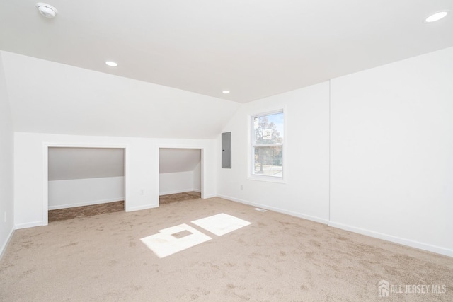 additional living space featuring electric panel, light colored carpet, and lofted ceiling