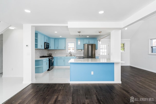 kitchen with appliances with stainless steel finishes, sink, a center island, pendant lighting, and blue cabinets