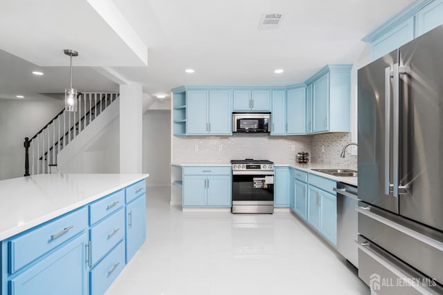 kitchen with appliances with stainless steel finishes, sink, backsplash, blue cabinets, and decorative light fixtures