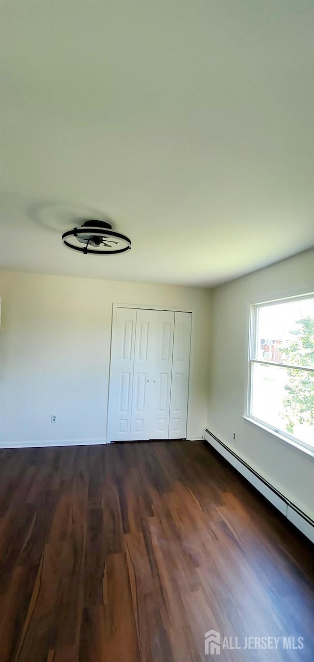 308 Codrington Pl, Bound Brook, NJ 08805 - unfurnished bedroom with baseboard heating, dark wood finished floors, and a closet