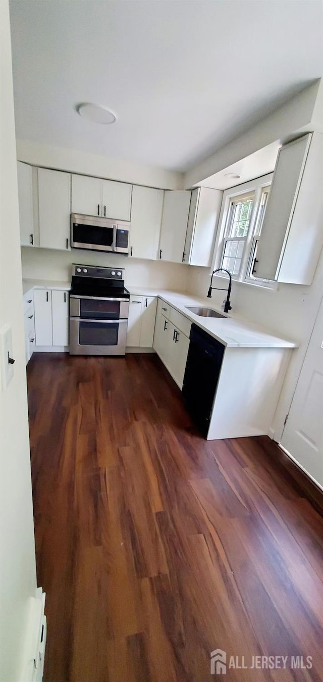 308 Codrington Pl, Bound Brook, NJ 08805 - kitchen with appliances with stainless steel finishes, dark wood-style flooring, white cabinetry, and light countertops