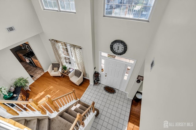 entrance foyer featuring a healthy amount of sunlight, visible vents, stairway, and wood finished floors