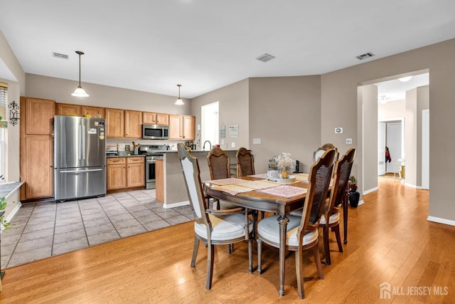 dining space with light wood-type flooring, baseboards, and visible vents