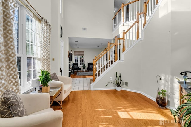 foyer with visible vents, a high ceiling, wood finished floors, baseboards, and stairs