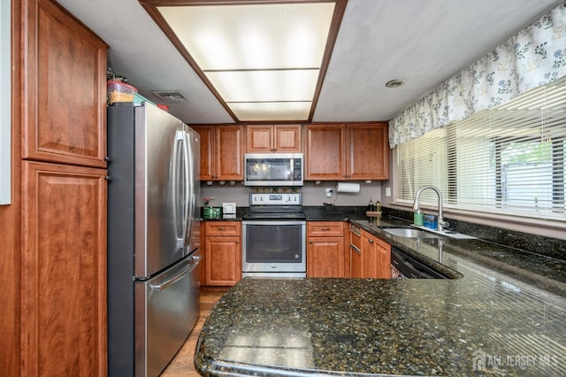 109-B Hemlock Plz, Monroe, NJ 08831 - kitchen with appliances with stainless steel finishes, dark stone countertops, brown cabinets, and a peninsula
