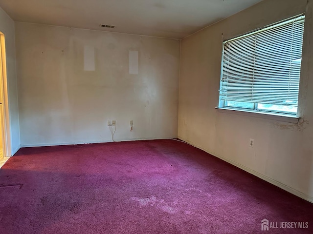 carpeted empty room featuring visible vents