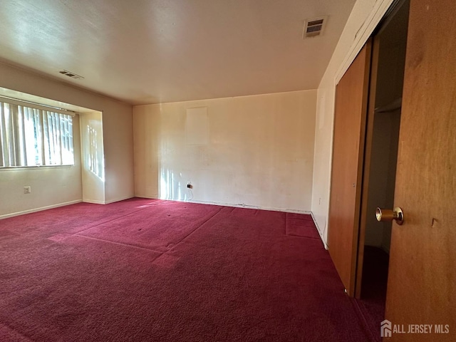 empty room featuring visible vents and dark carpet