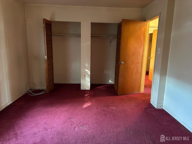 unfurnished bedroom featuring two closets and carpet floors