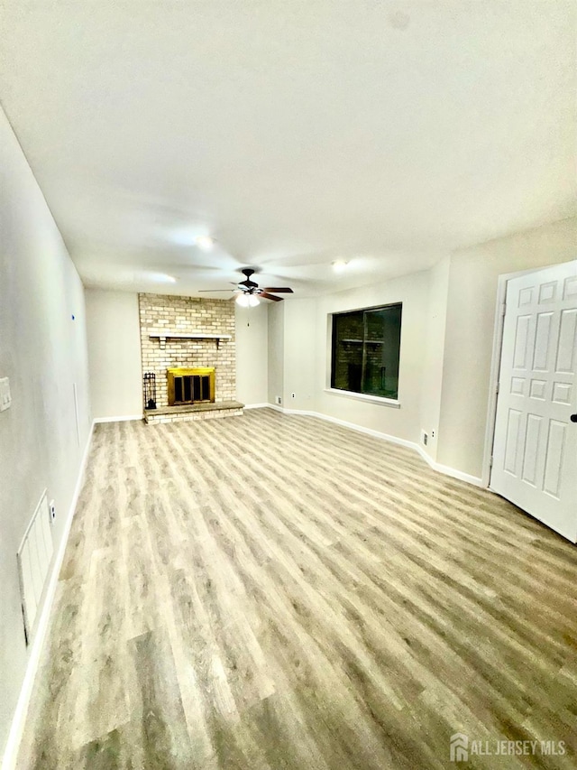 unfurnished living room featuring ceiling fan, wood-type flooring, and a fireplace