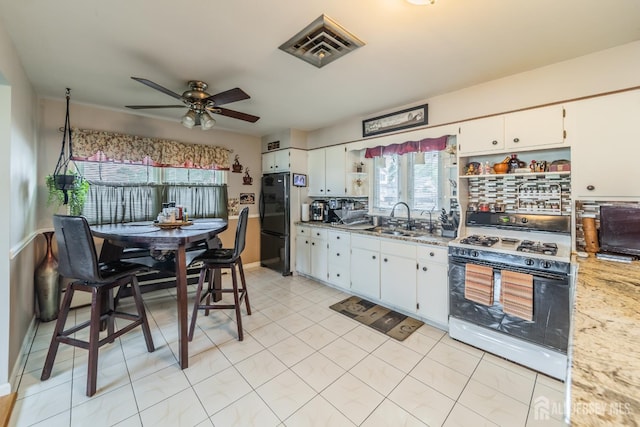 119 Carteret Ave, Carteret, NJ 07008 - kitchen featuring gas range, freestanding refrigerator, open shelves, a ceiling fan, and white cabinets