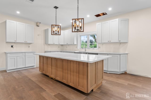 38 Louise Dr, East Brunswick, NJ 08850 - kitchen featuring a chandelier, light wood finished floors, light countertops, a kitchen island, and white cabinetry