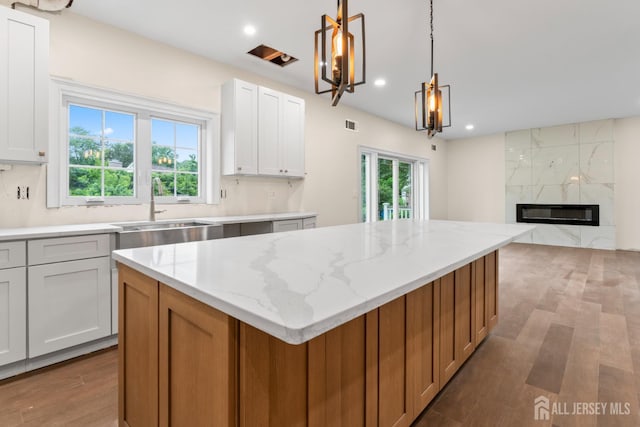 38 Louise Dr, East Brunswick, NJ 08850 - kitchen with wood finished floors, a kitchen island, light stone counters, recessed lighting, and hanging light fixtures