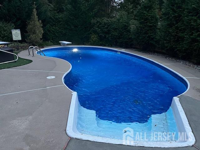 outdoor pool featuring a patio area and a diving board