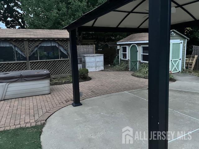 view of patio featuring a hot tub and a storage unit