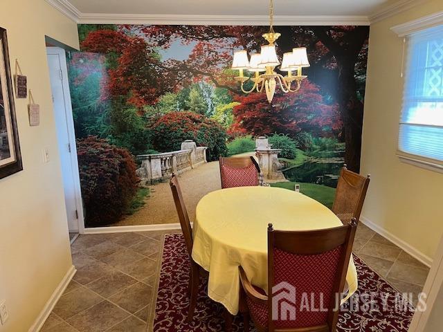 dining space with a chandelier, ornamental molding, tile patterned floors, and baseboards