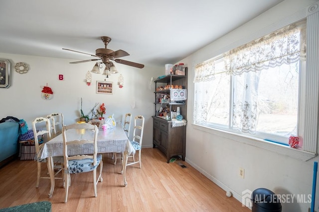 dining space with a ceiling fan, light wood-type flooring, and baseboards