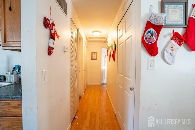 hallway with light wood finished floors and visible vents