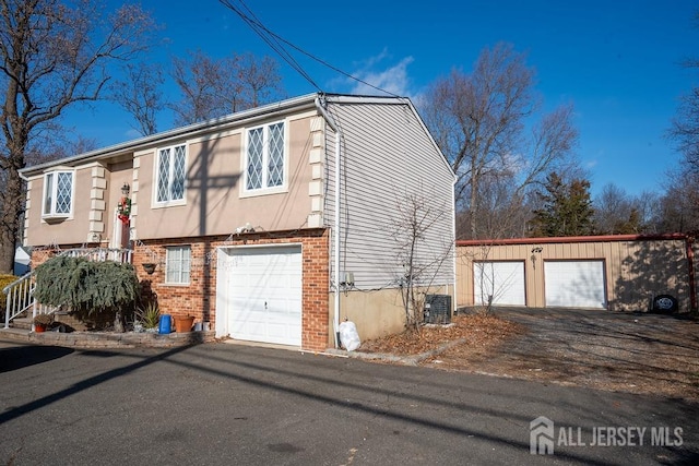 view of side of property featuring a garage, brick siding, and central AC unit