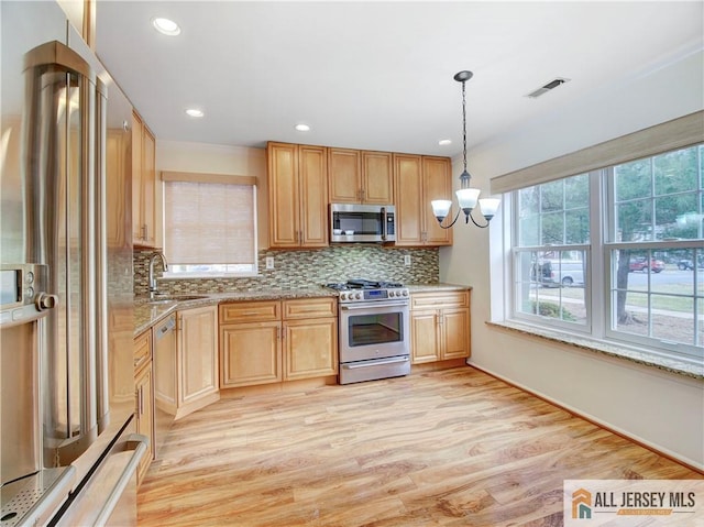 kitchen featuring sink, premium appliances, decorative light fixtures, light wood-type flooring, and light brown cabinets