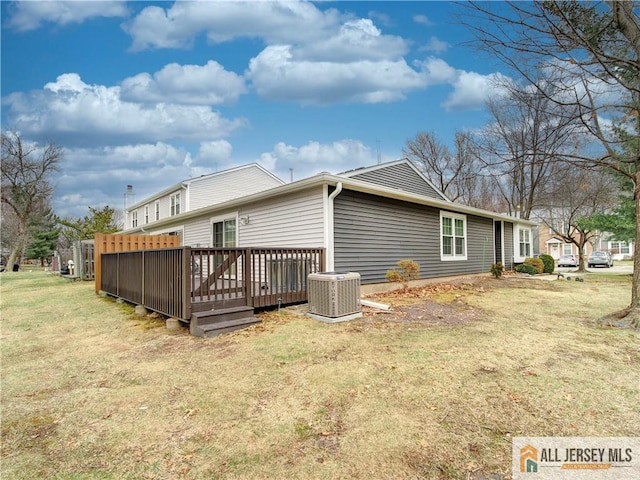 rear view of property featuring a wooden deck, cooling unit, and a lawn