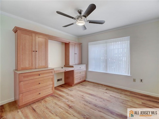 unfurnished office with ornamental molding, built in desk, ceiling fan, and light hardwood / wood-style floors