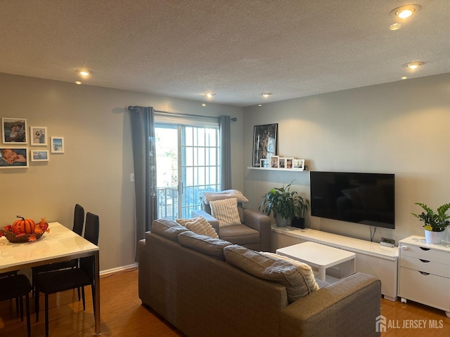 living room with recessed lighting, wood finished floors, and a textured ceiling