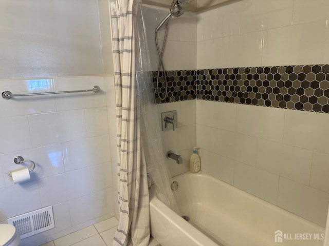 full bathroom with toilet, shower / bathtub combination with curtain, visible vents, and tile walls