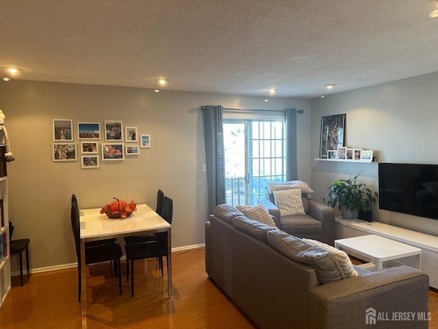 living room with baseboards, wood finished floors, a textured ceiling, and recessed lighting