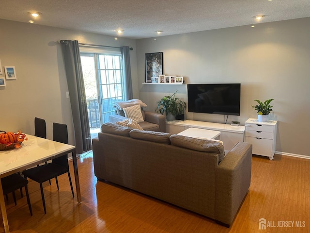 living room featuring recessed lighting, wood finished floors, a textured ceiling, and baseboards