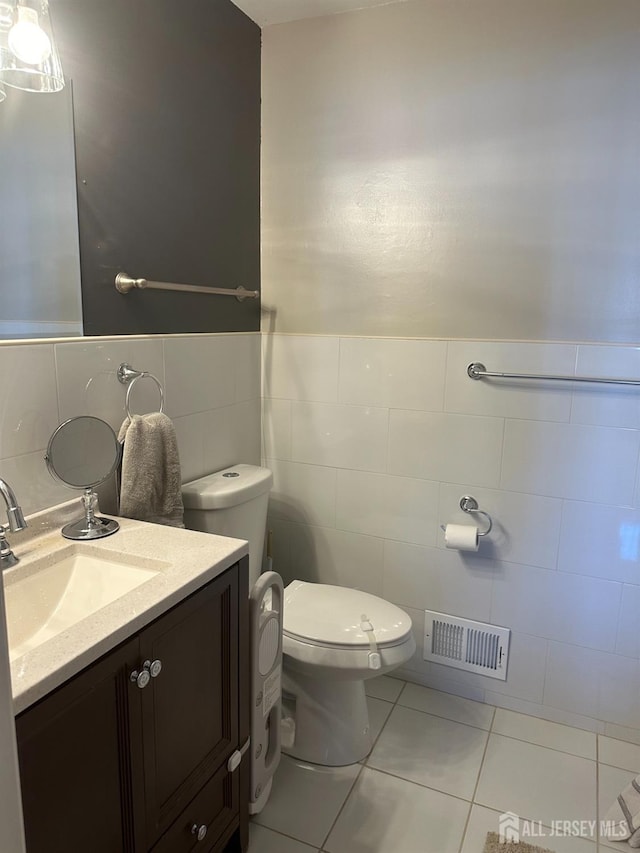 bathroom featuring tile walls, visible vents, toilet, and vanity