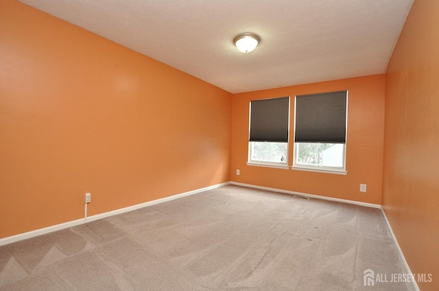 carpeted empty room featuring a textured ceiling, visible vents, and baseboards