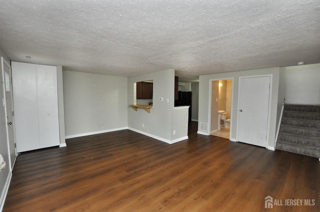 unfurnished living room with dark hardwood / wood-style flooring and a textured ceiling