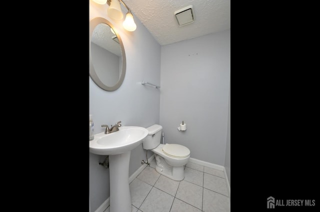 bathroom with tile patterned flooring, sink, a textured ceiling, and toilet