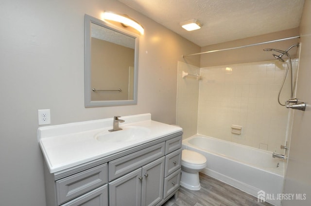 full bathroom with hardwood / wood-style floors, vanity, a textured ceiling, shower / washtub combination, and toilet