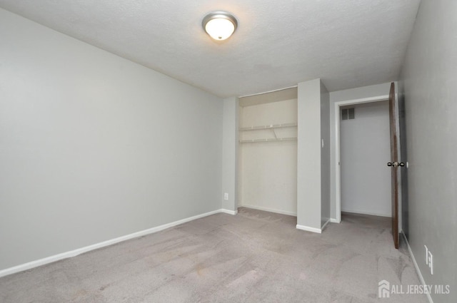 unfurnished bedroom featuring a closet, light carpet, and a textured ceiling