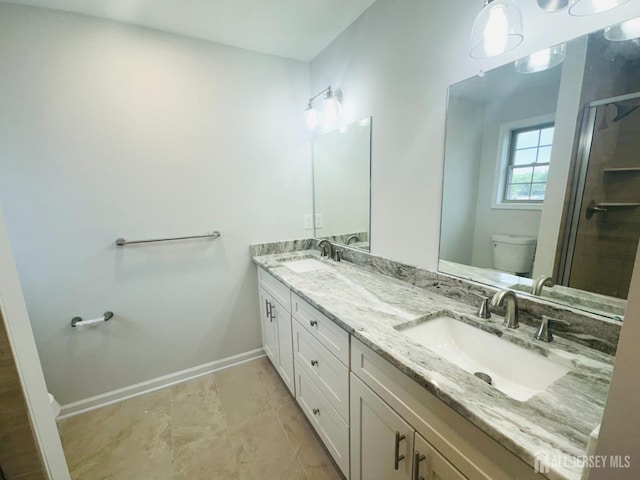 bathroom featuring toilet, a shower stall, baseboards, and double vanity