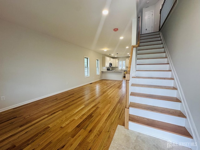 stairway with wood finished floors, baseboards, and recessed lighting
