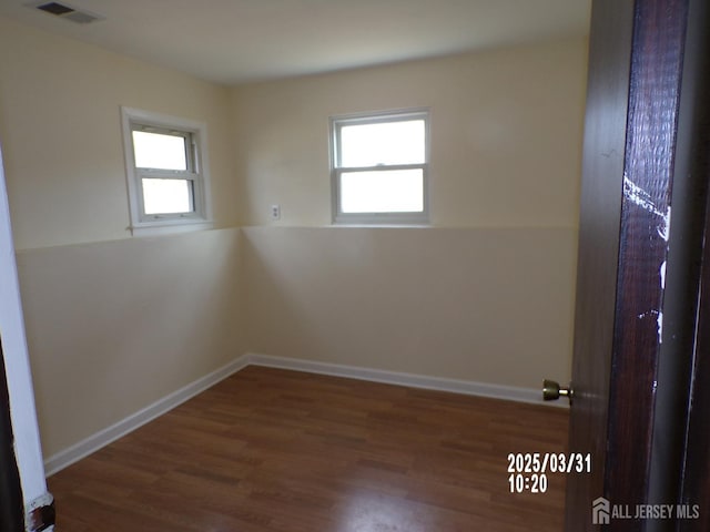 spare room with visible vents, plenty of natural light, and wood finished floors