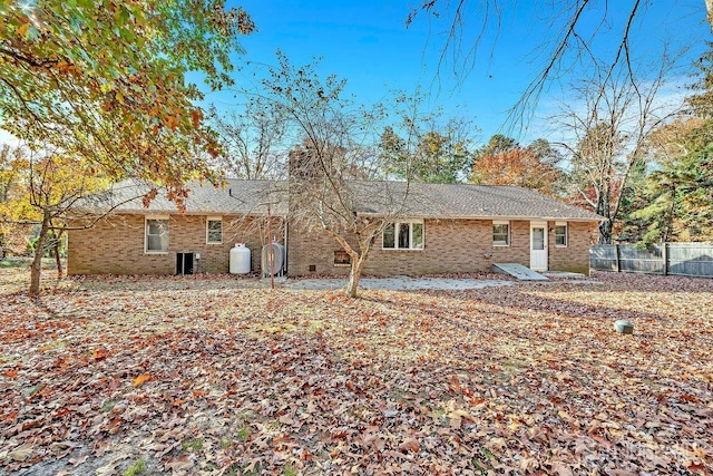 back of house featuring brick siding and fence